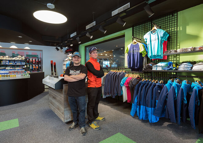 Zwei Personen stehen zusammen in einem modernen Sportbekleidungsgeschäft, umgeben von Regalen mit Kleidung und Accessoires.