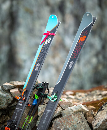 2 Skier mit Stöcke lehnen an einem Steinhaufen im Freien.