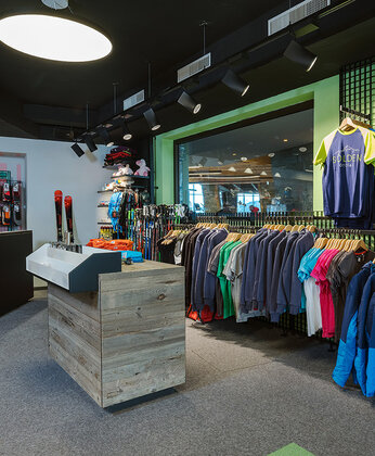 Ein Bekleidungsgeschäft mit Regalen mit bunten Bekleidung, einem hölzernen Tresen und einem großen Schaufenster, in dem sich das Geschäft spiegelt.