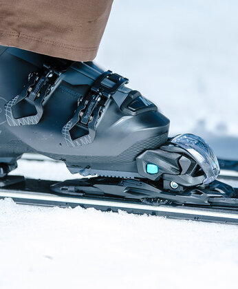 Nahaufnahme eines Skischuhs, der der in einer Skibindung fixiert ist.