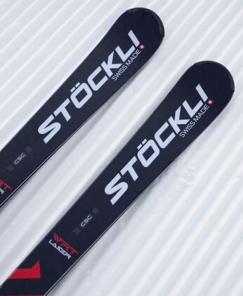 Nahaufnahme von zwei schwarzen Stockli-Skiern, die auf präpariertem, strukturiertem Schnee liegen.